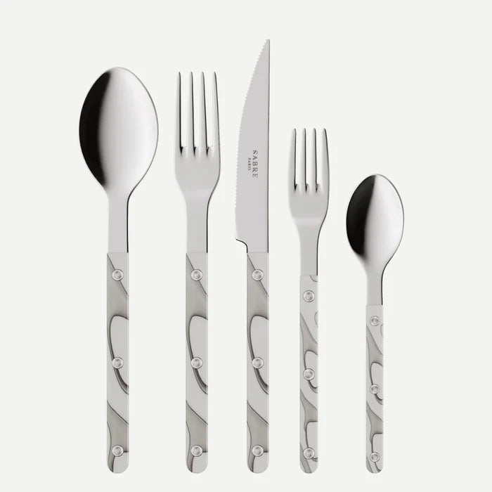 The Sabre Bistro Dune Flatware 5 Piece Setting features 18/10 stainless steel heads and patterned metal handles, including a large spoon, dinner fork, serrated knife, small fork, and small spoon displayed side by side on a white background.