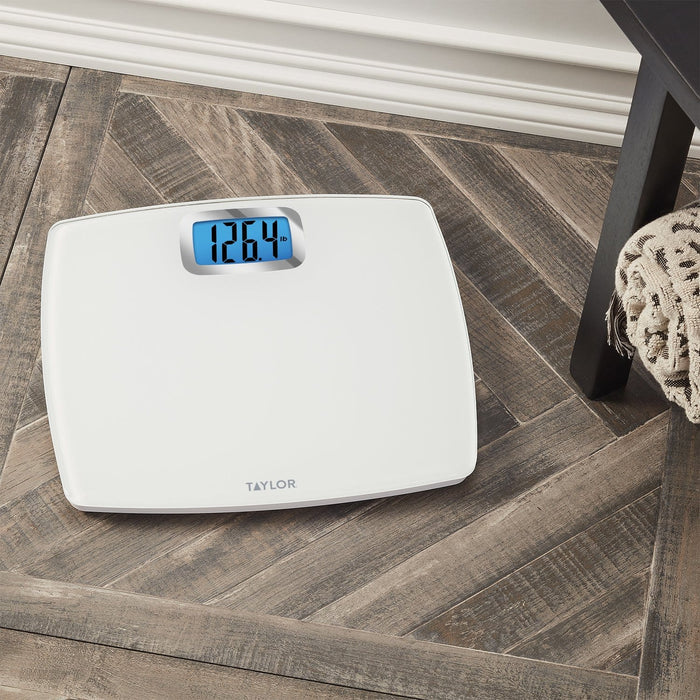 Angled top view of a white digital bathroom scale on a wood floor with a blue display showing 126.4 lb